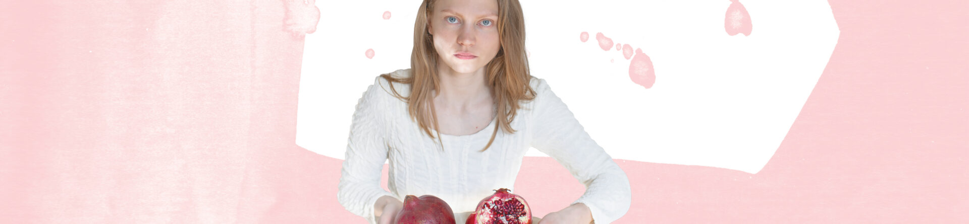 Noor naine hoidmas käes pooleks murtud granaatõuna