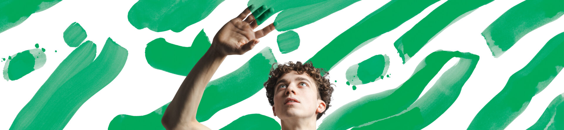 Lokkis juustega noormees värvilaikude taustal, sõrmed värvist rohelised